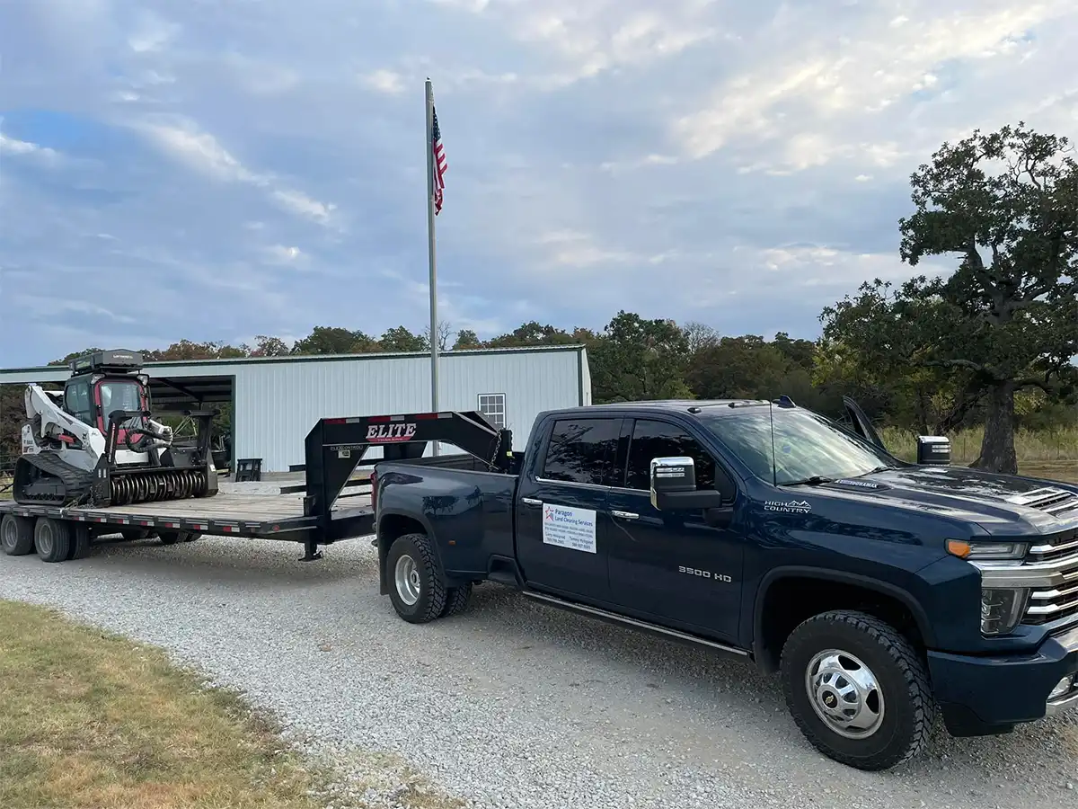 pickup truck towing a trailer with a brush hogger