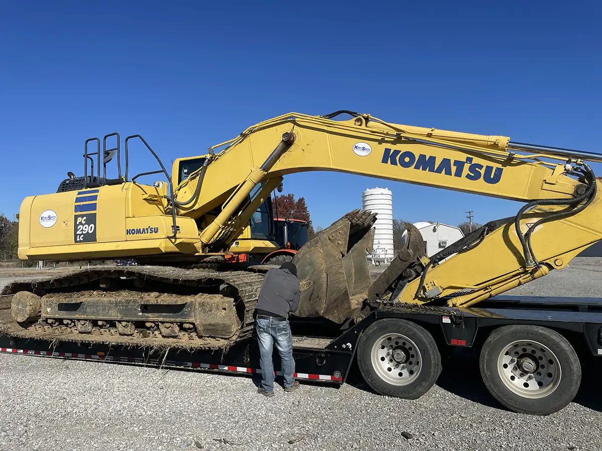 man servicing an excavator on a truck